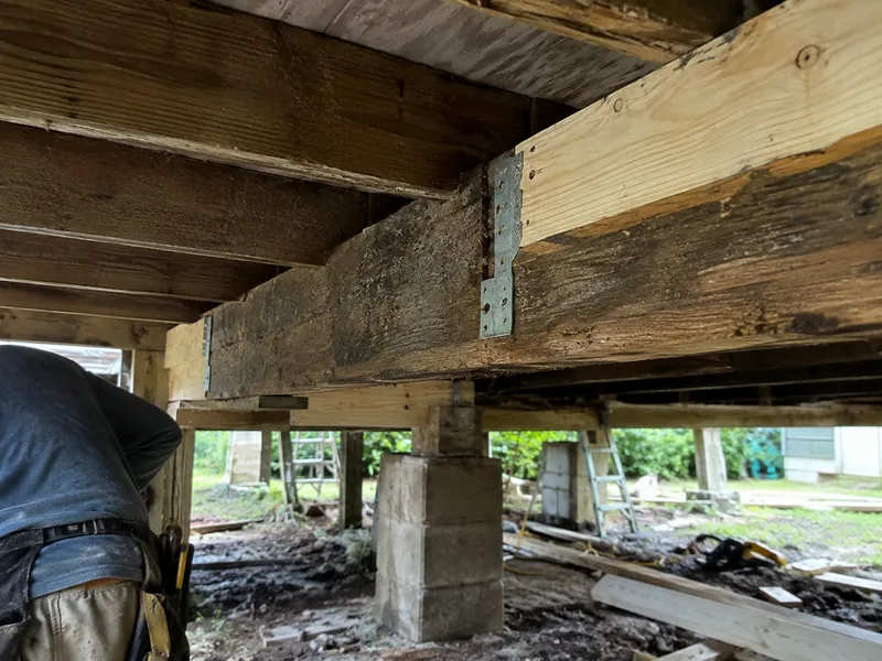 New lumber sistered to an old floor joist under a raised house
